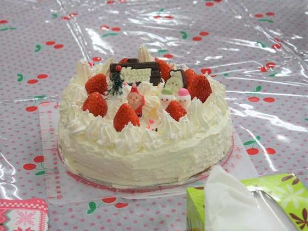 イチゴのショートケーキ（ホール）の上には色とりどとりのサンタが４人・クリスマスツリー・「Merry Christmas」と書かれたチョコプレート。が乗っている