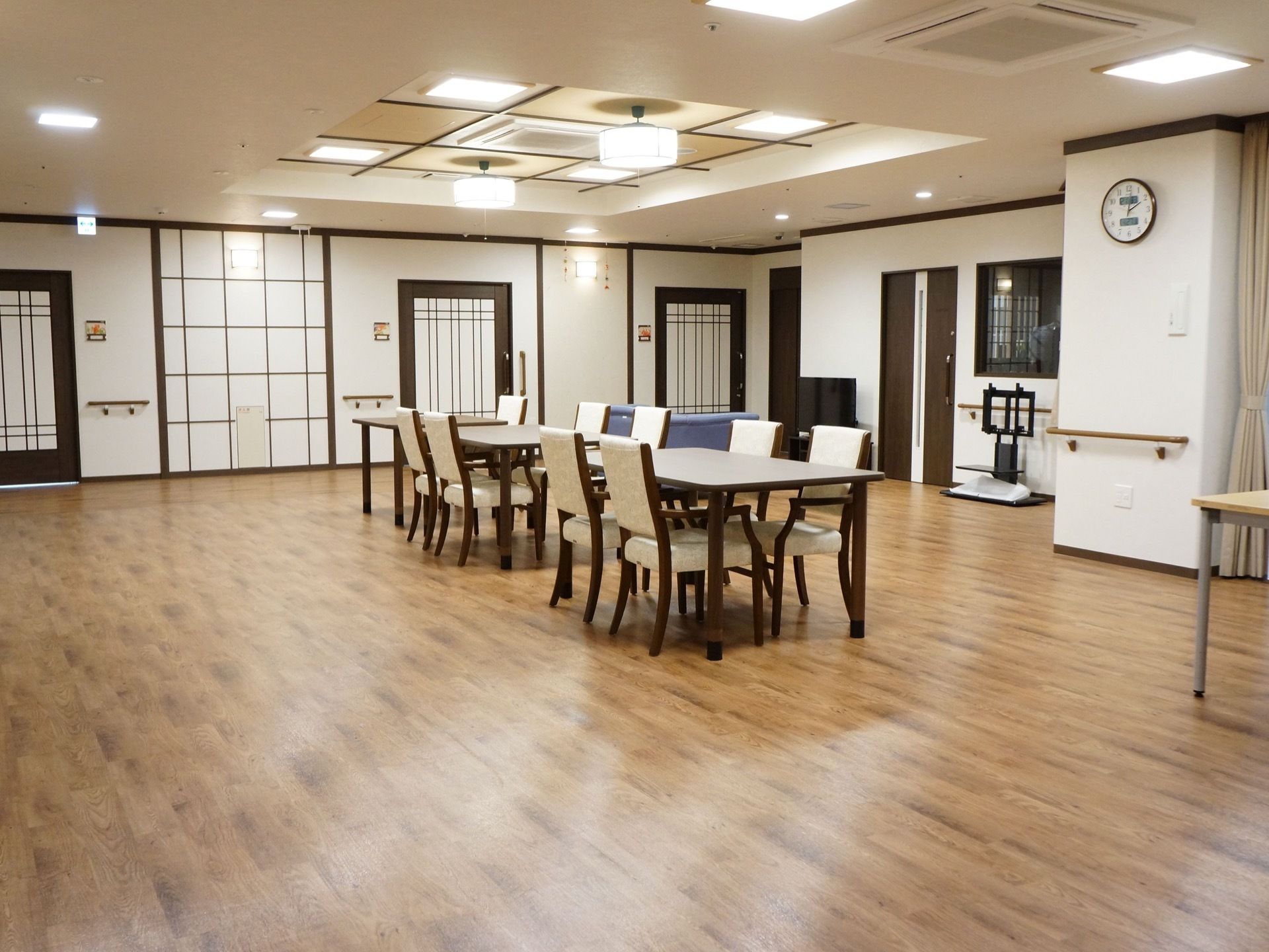 広々としていておしゃれな食堂。部屋の中心にはテーブルが３脚置かれている。青いソファの前にテレビがある。