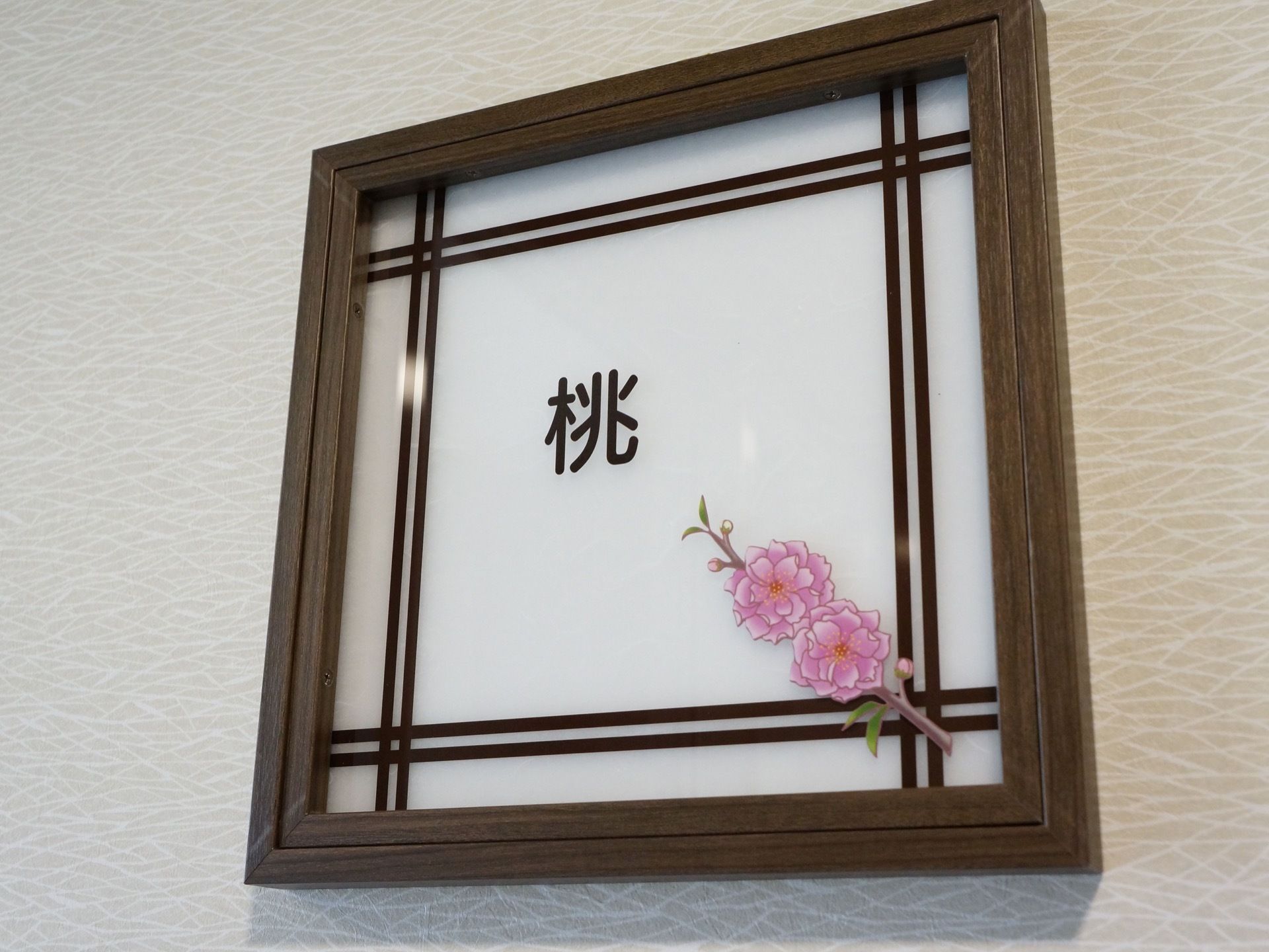 部屋の名前が書かれた障子をイメージしたプレート。部屋の名前は日本の花の名前が選ばれていて、桃の絵が描かれている。