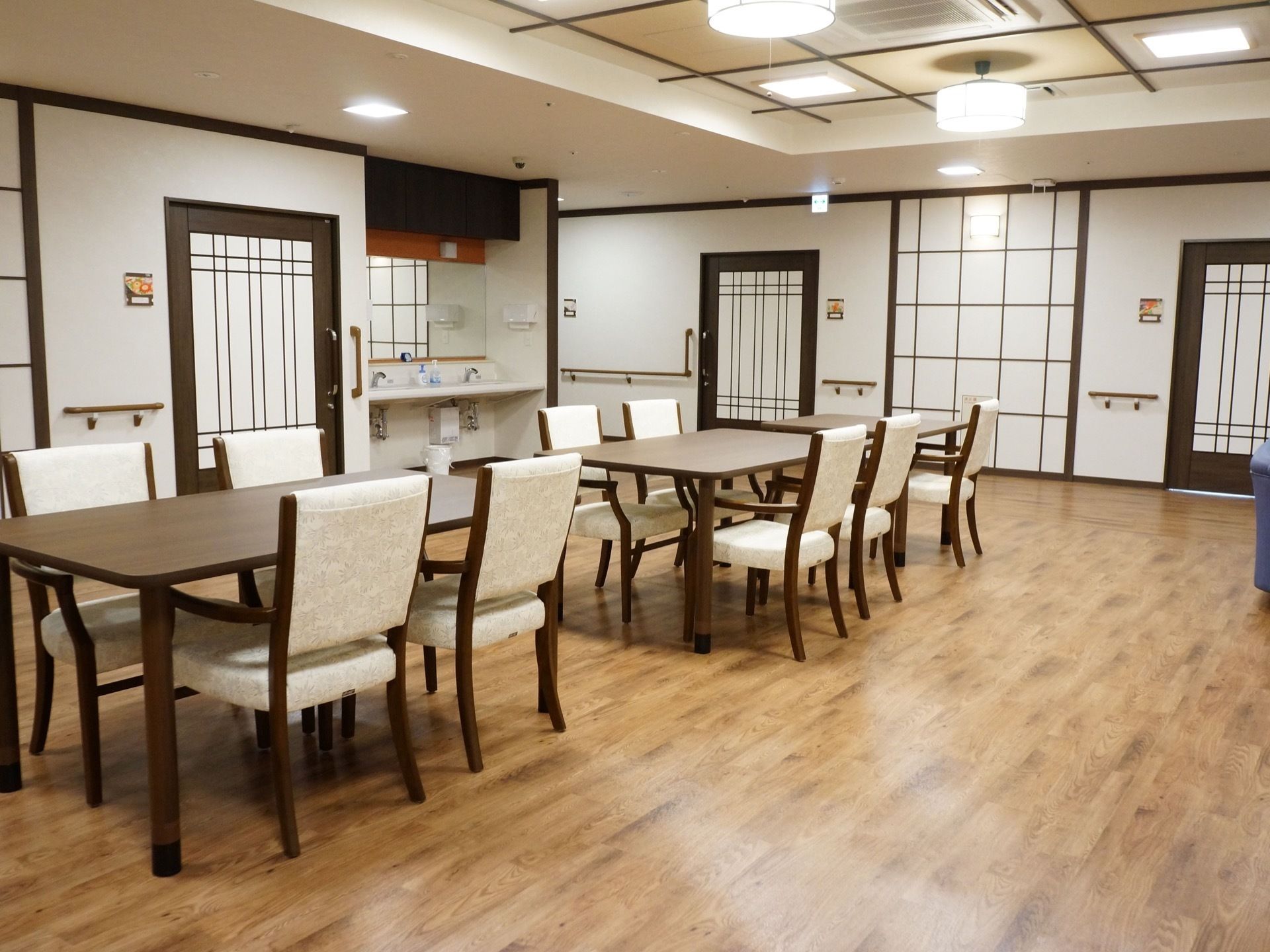 主に食堂として活用している共有スペースには、ダイニングテーブルと椅子が並列にセッティングされ、壁側には手洗い用の洗面台が設置されている。