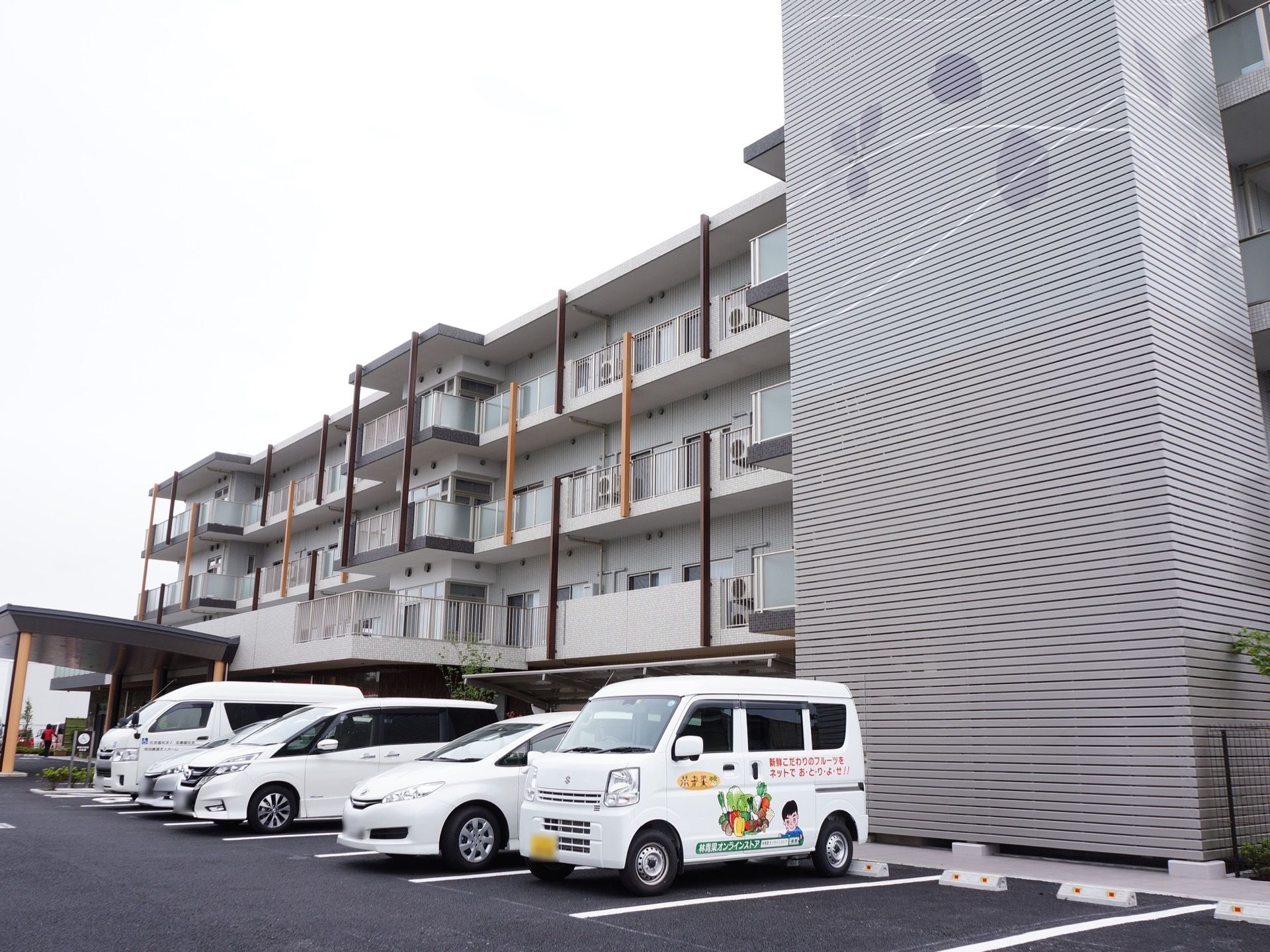 施設の建物は、１階から４階までを覆う大きなグレーの外壁に、桜の花が同色の濃淡で描かれている。また、敷地内には駐車場が完備されている。