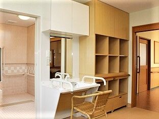 椅子と手すりがついた洗面台と脱衣所がある浴室の様子