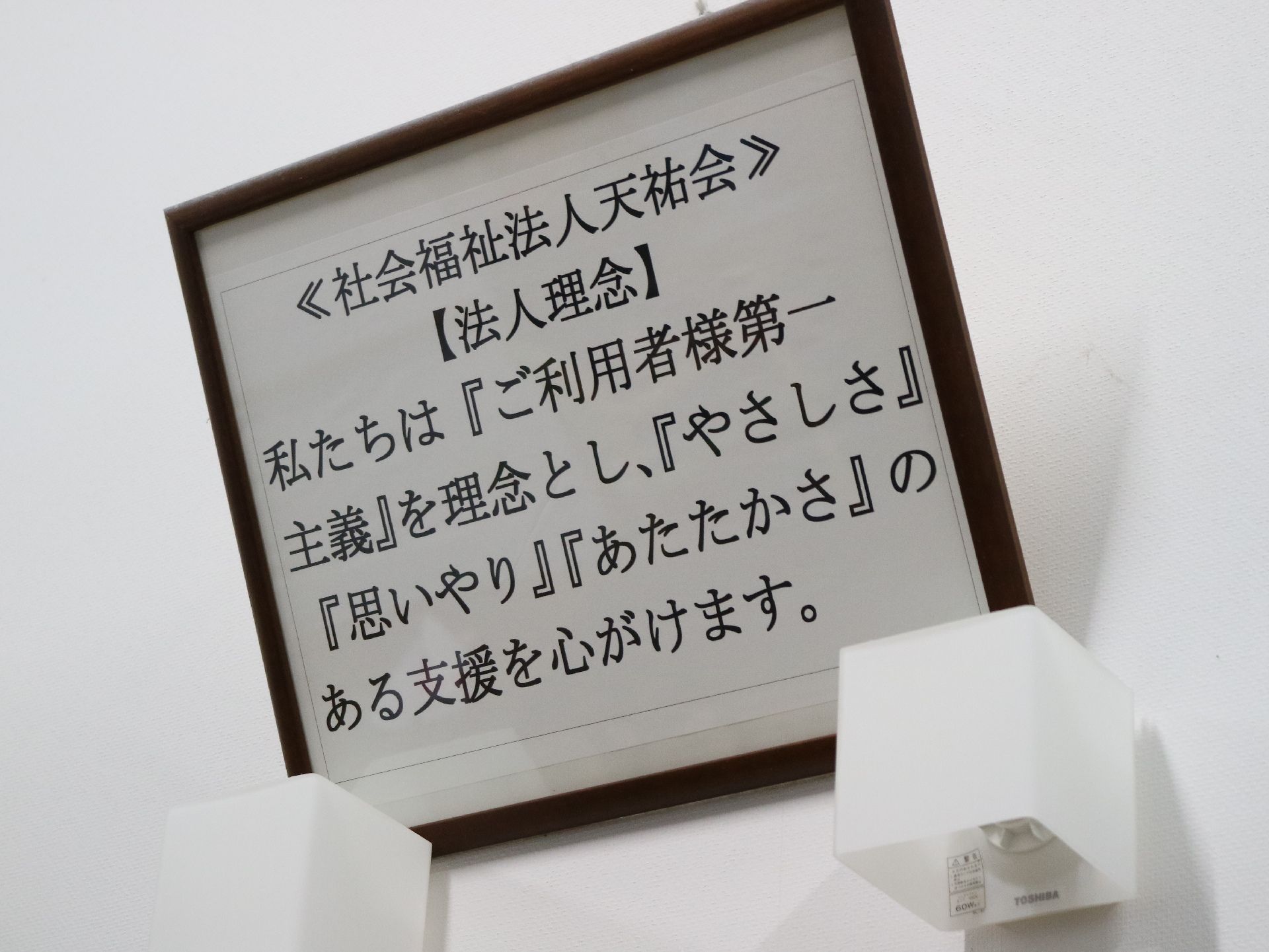 スタッフが高齢者に寄り添う様子。スタッフも高齢者も微笑んでいる。ベッドの上に横たわっているがとても表情が良い感じ。