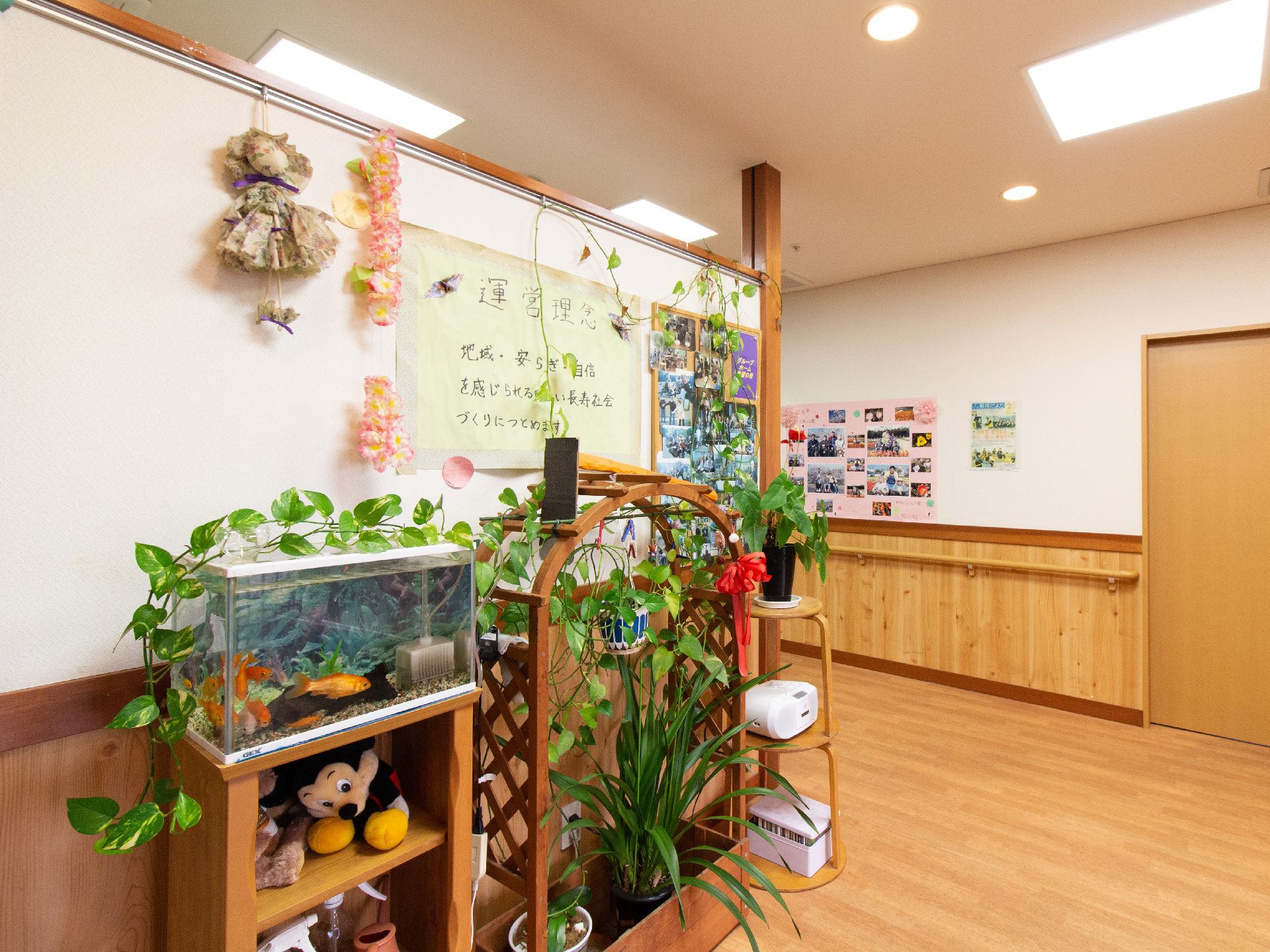 運営理念を掲示した壁と植物や水槽を配置した共有スペース
