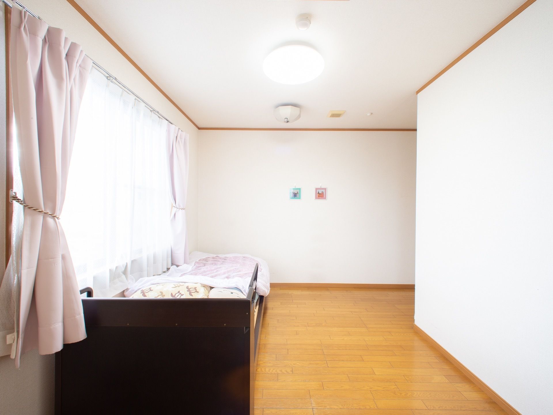 居室は、広々としたスペースがある。左側には、ピンク色のカーテンが掛かった大きな窓がある。
