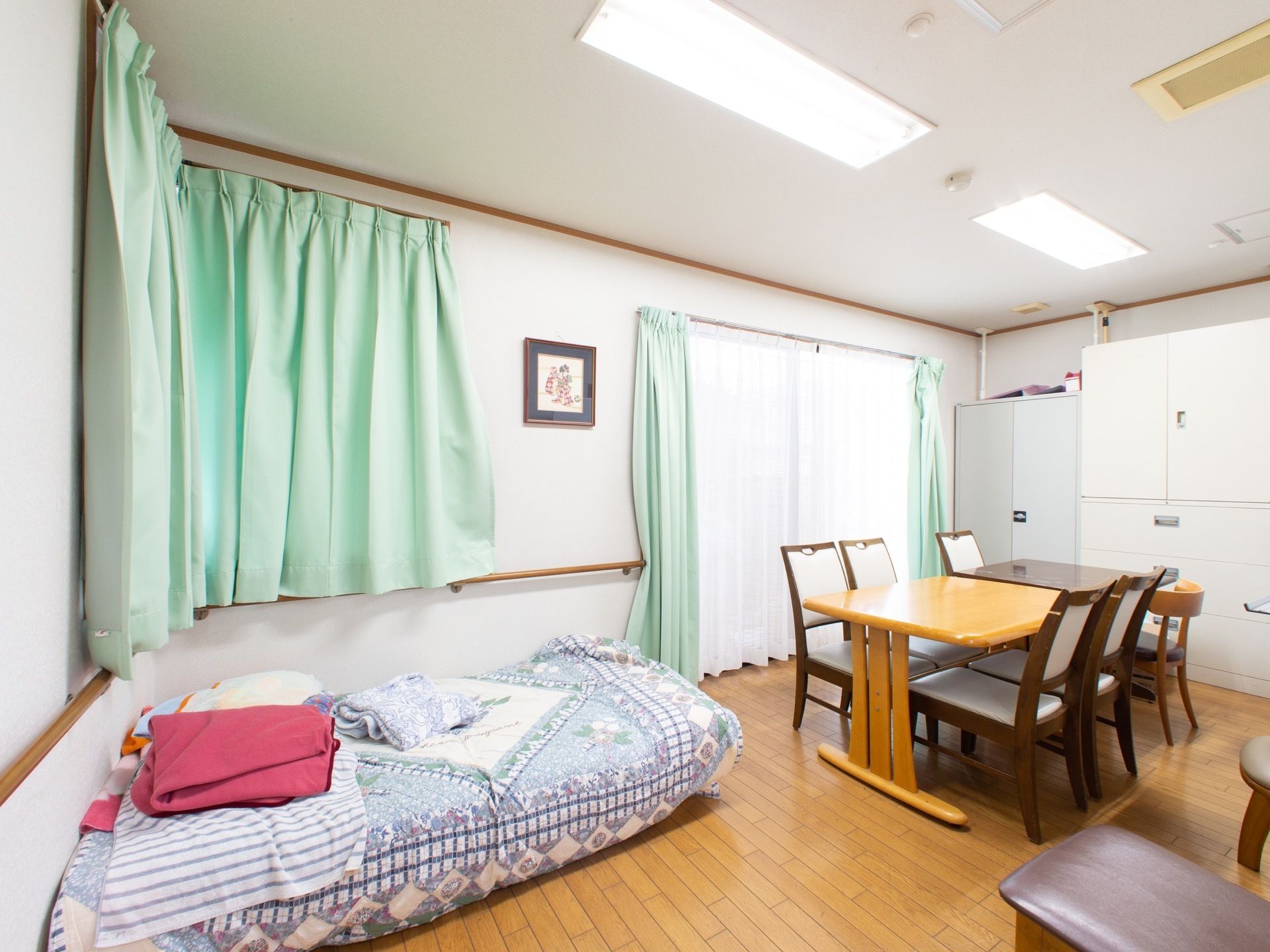 施設内にはリビングがあり、テーブルや椅子がたくさん並べられている。部屋の隅には、大きなベッドも置かれている。