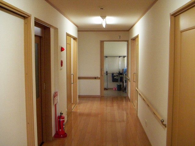 消火器や防災設備が設置された廊下は幅が広く、手すりが設置されている。木目調が優しい雰囲気。