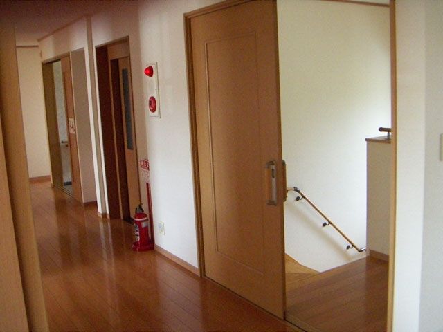 防災設備が設置されたまっすぐな廊下には何も置かれていない。手前には階段も設置されている。