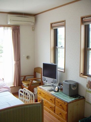 介護ベッドやエアコンが設置された部屋にはタンスやテレビもあり、カーテンが付いた窓もある。
