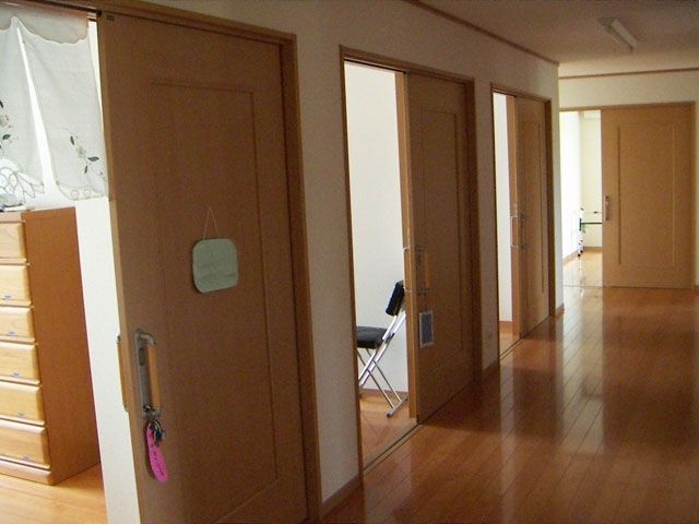 引き戸が付いた居室が複数並んでいる。手前には暖簾が設置されていて、その奥の部屋にはいすが置かれている。