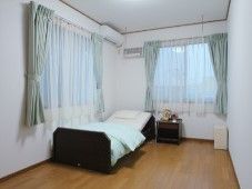 カーテンが付いた部屋。ベッド、エアコン、小さな家具