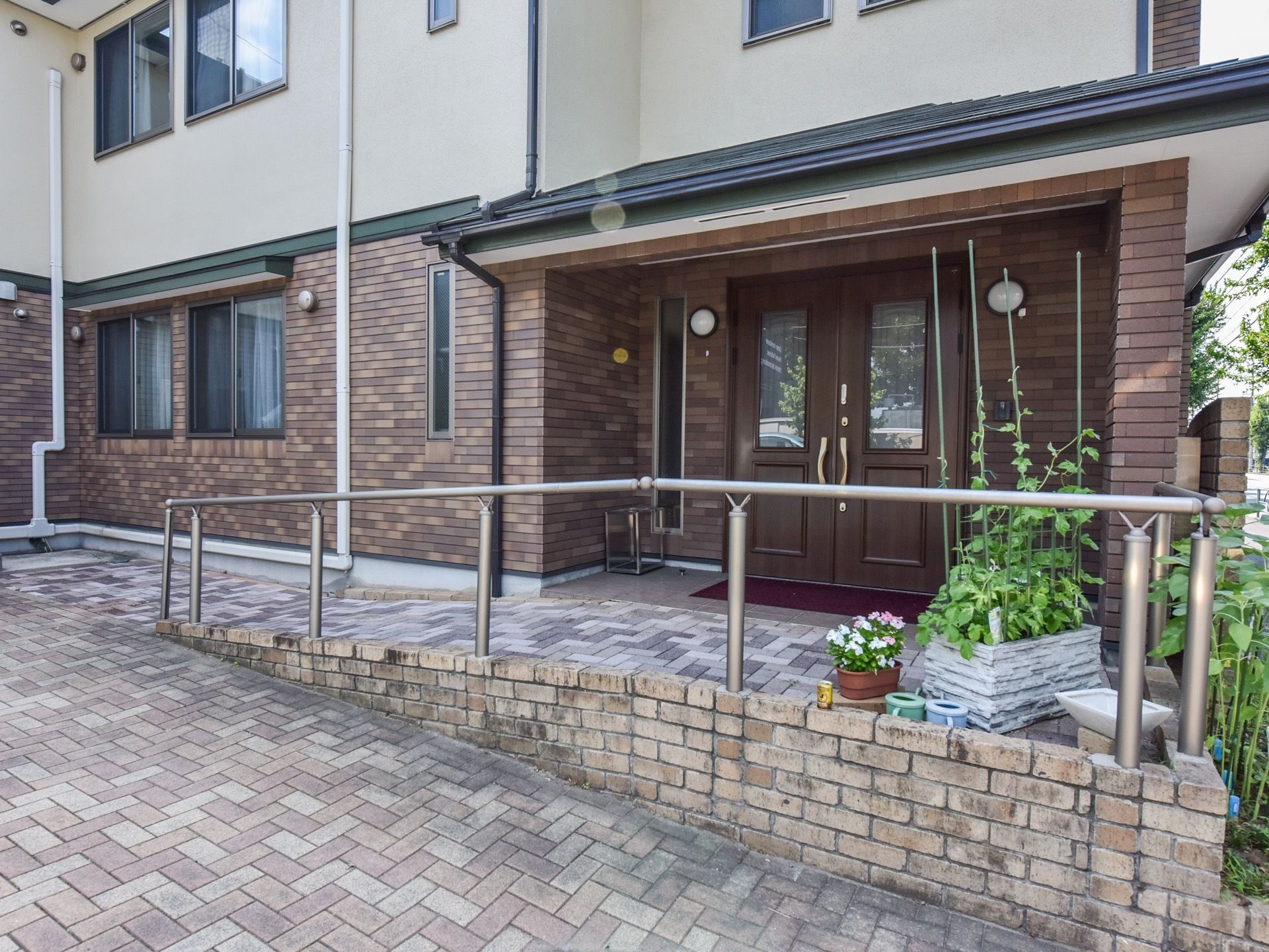 施設の建物は、１階部分がレンガ調、２階部分がベージュ色の外壁で、洗練された印象である。玄関は両開きの木の扉となっている。