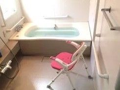 一人用の小さな浴槽とシャワーチェアが置いてある浴室。よくある家庭サイズの浴室