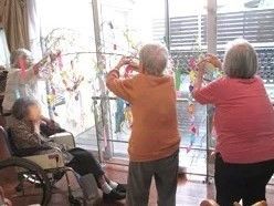 施設内で飾りつけをしている様子。複数名が笹の葉っぱに何かを取り付けている様子が分かる