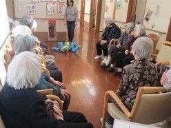 施設内で集まり、レクリェーションに取り組んでいる様子。スタッフが説明している様子が分かる