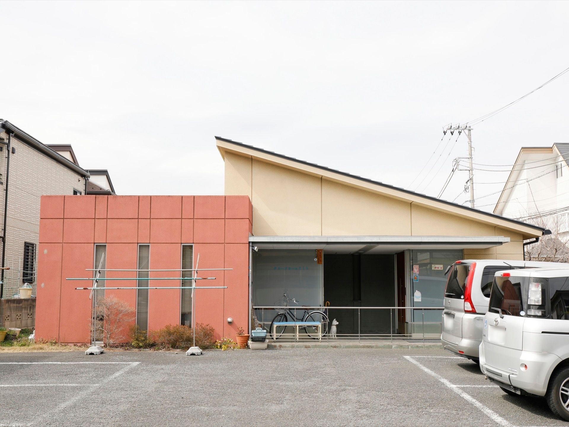 斜めの屋根が特徴的な平屋建ての施設である。建物前に広い駐車スペースが設けられている。物干し台が設置されている。