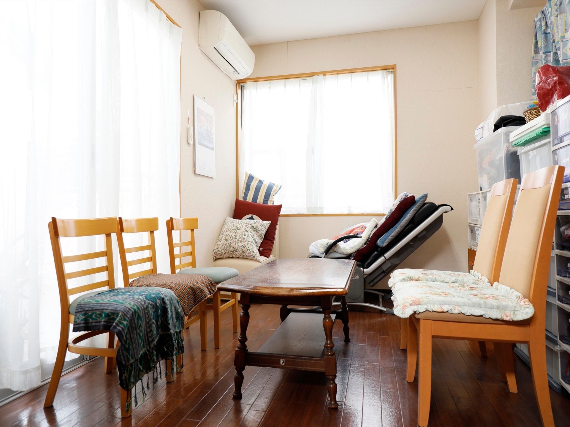 大きな掃き出し窓と腰高の窓がある談話室がある。ローテーブルと椅子が５つ置かれている。窓際にリクライニングチェアがある。
