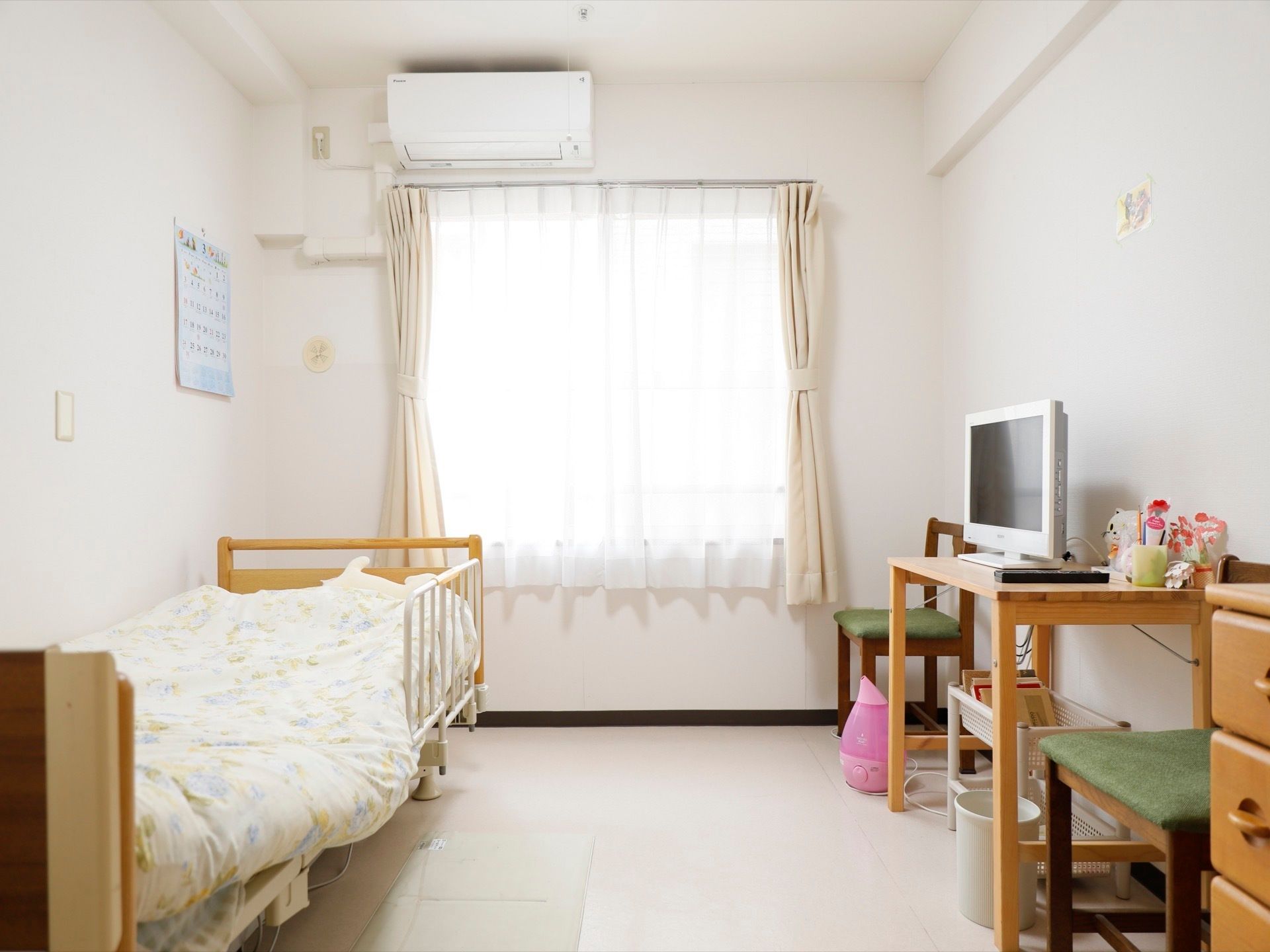 白色を基調とした明るい居室である。エアコンやベッドが完備されている。ベッドの近くの床にはマットが敷かれている。