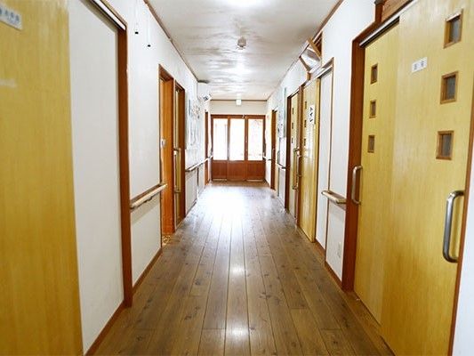 まっすぐに続く廊下に手すりが取り付けてある。両側に引き戸の部屋