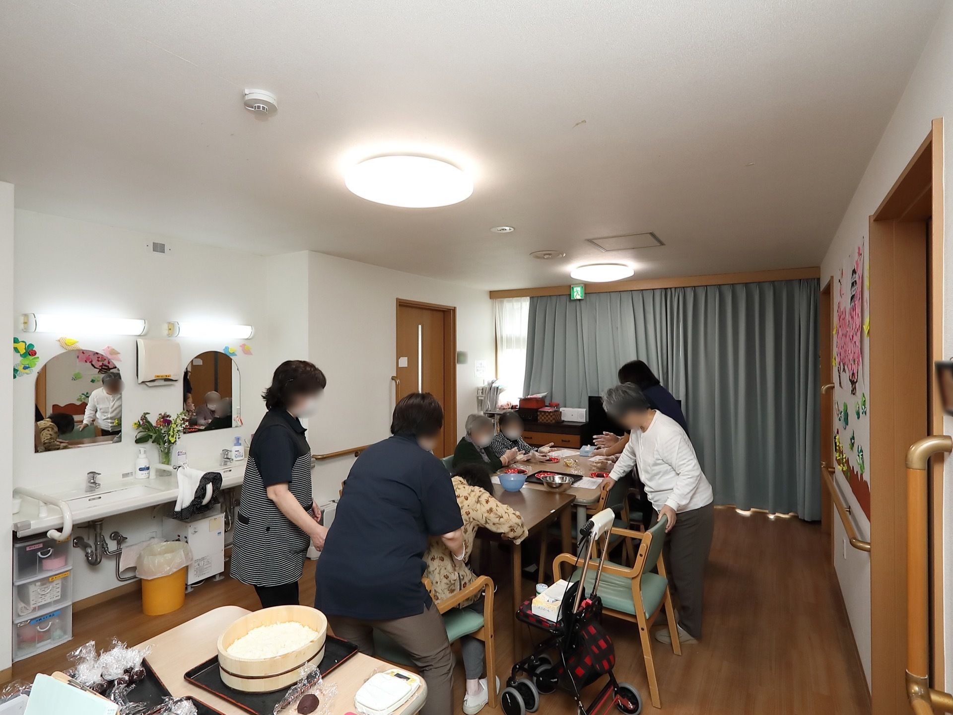 共有スペースの奥にある窓にはグレーのカーテンが掛けられている。中央にあるダイニングテーブルで料理が作られている。