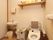 個室トイレには可動式の手すりが取りつけられている。左奥に洗面台があり、ハンドソープやペーパータオルが設置されている。