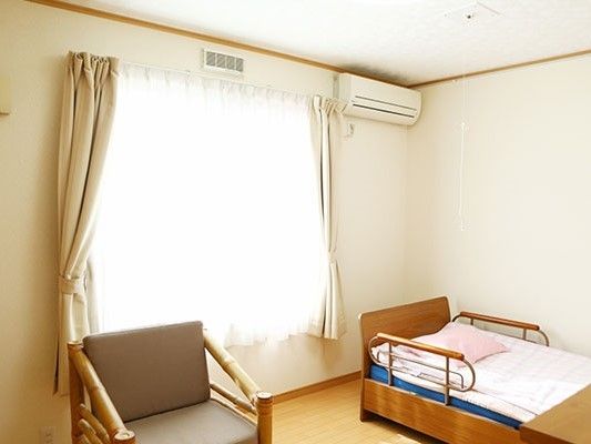 エアコン、窓、介護用ベッド、いすが並んでいる居室の様子。完全個室