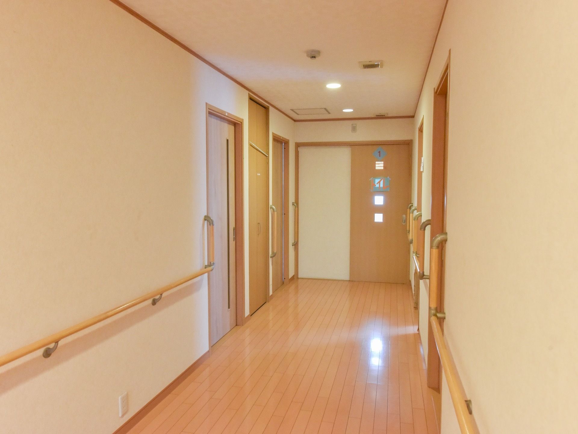 フローリングの廊下は幅広で、各居室への入り口への壁には手すりが設置されている。廊下もしっかりと調光されており安全に移動できる。