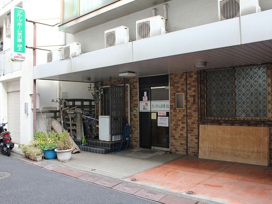 ホーム名が書かれているドアが付いた建物の玄関周りには草木が植えられている鉢がたくさん置かれている。