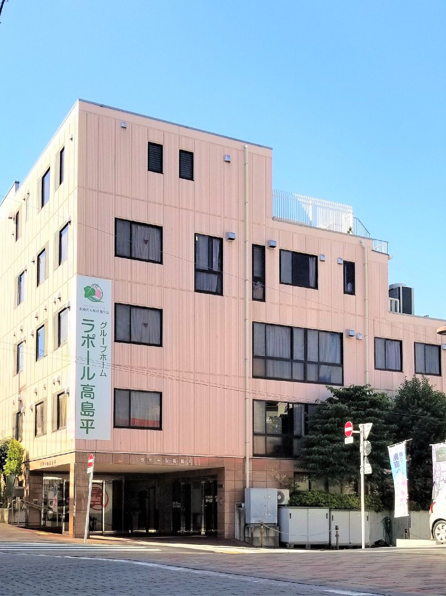 寝ている高齢者の女性に笑顔で話しかける女性スタッフは花柄エプロンを付けている。