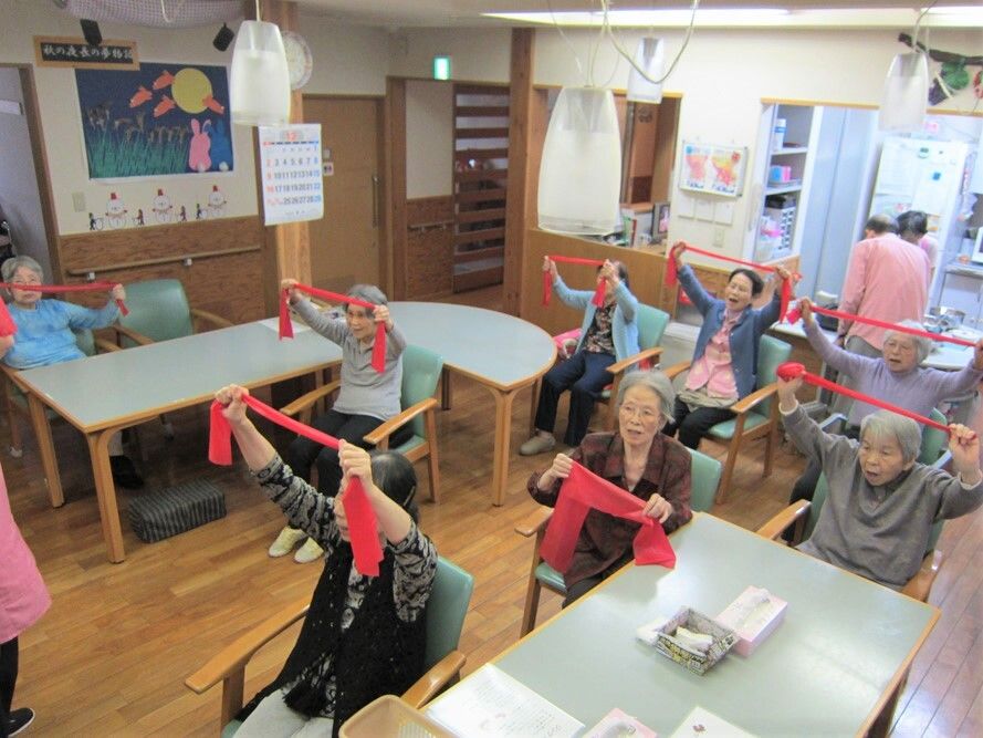 タオルのようなものをもって体操している施設入居者の様子。リハビリの一場面