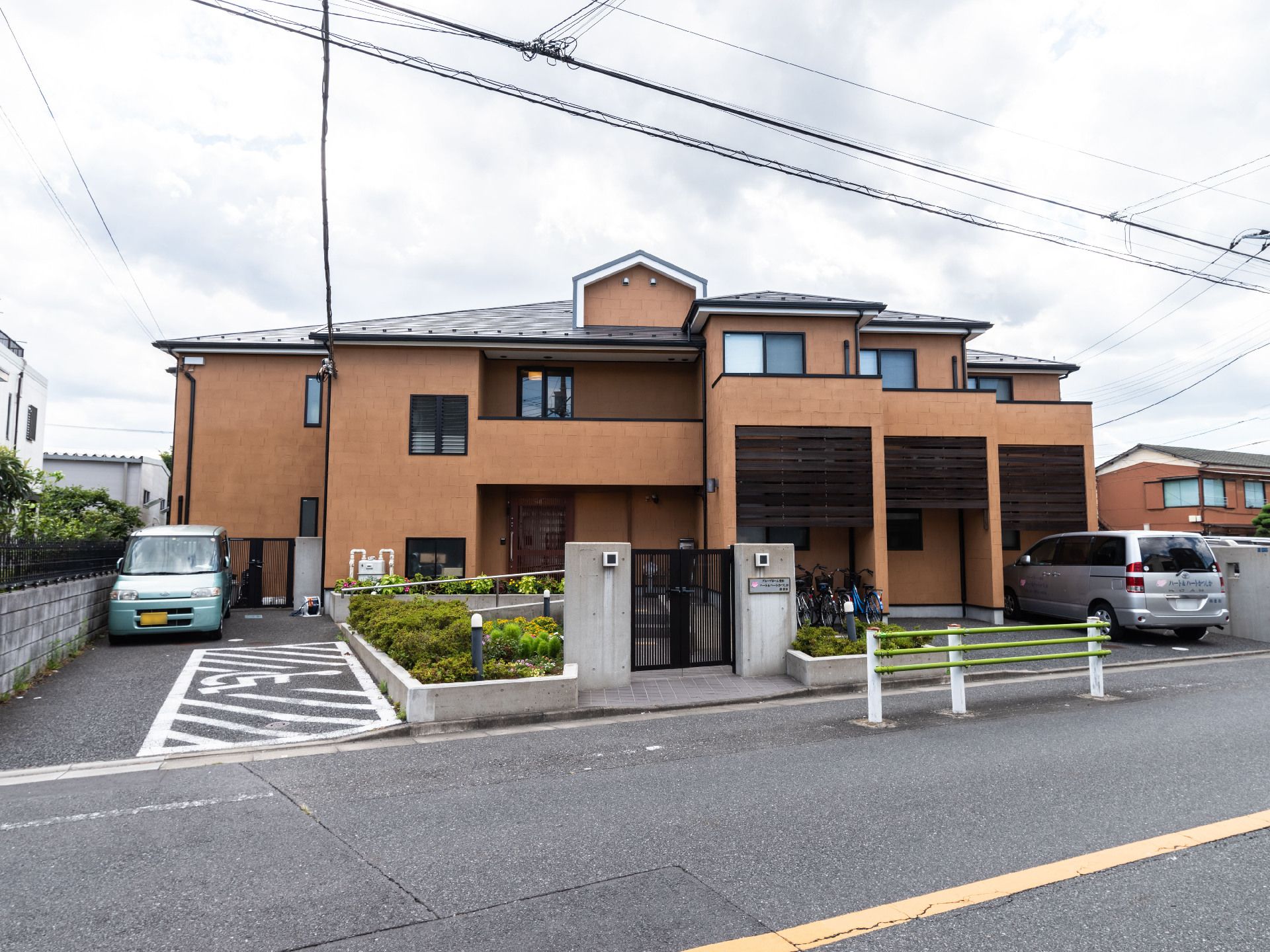 茶色の建物とそばに止まったブルーの軽自動車