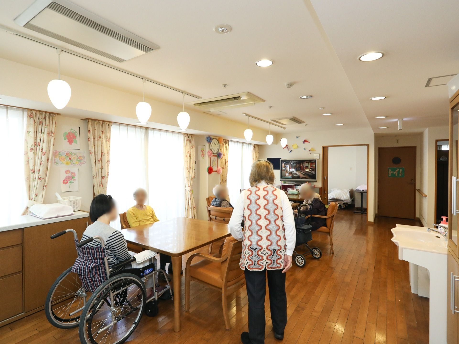 掃き出し窓が設置された、日当たりのいい共有スペースである。天井に埋め込み型の空調機を完備。テーブルと椅子がある。。