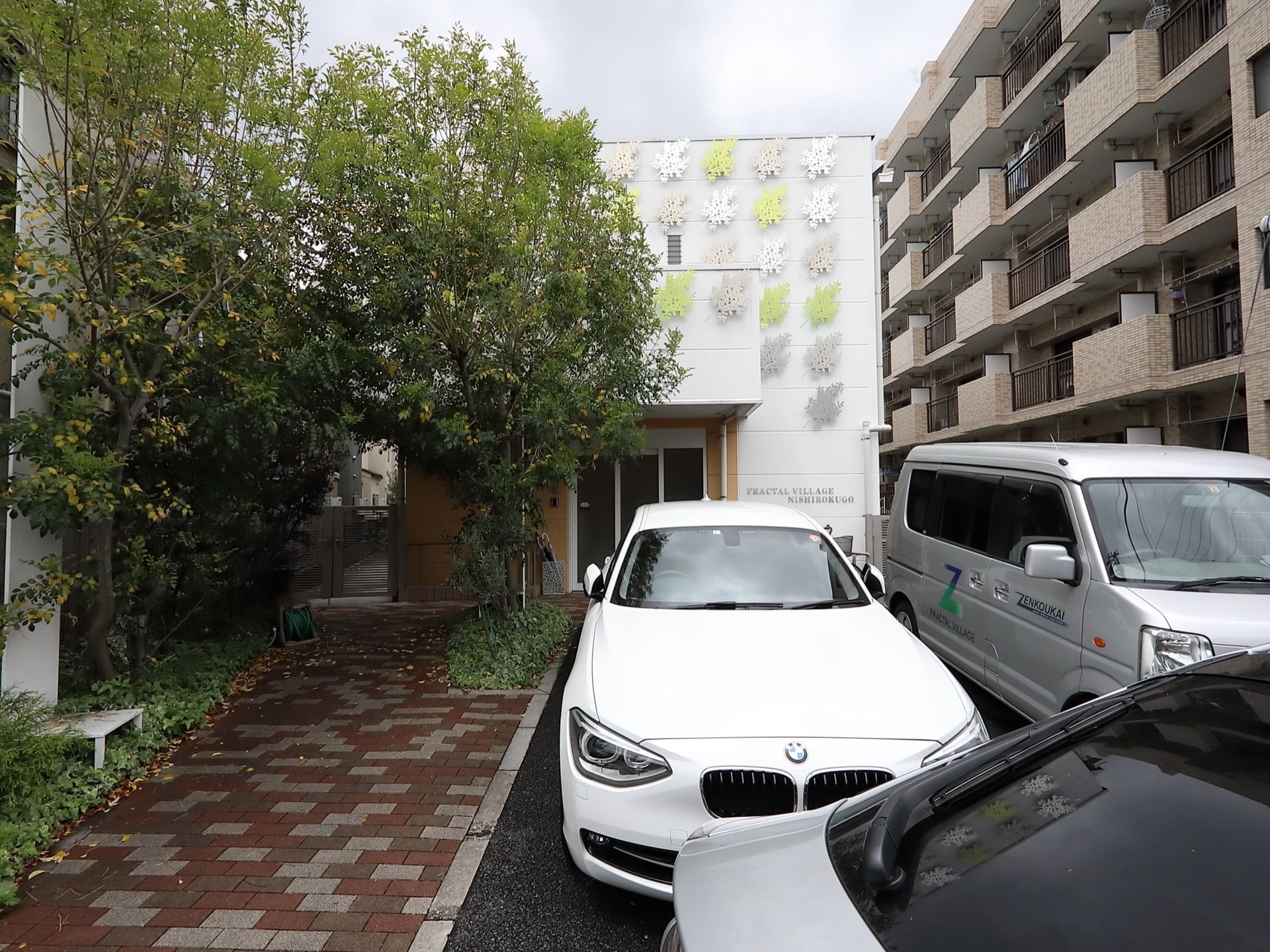 施設はモダンな白い２階建ての建物である。建物前に駐車場が設けられている。左側の玄関アプローチには、レンガ調タイルが敷かれている。