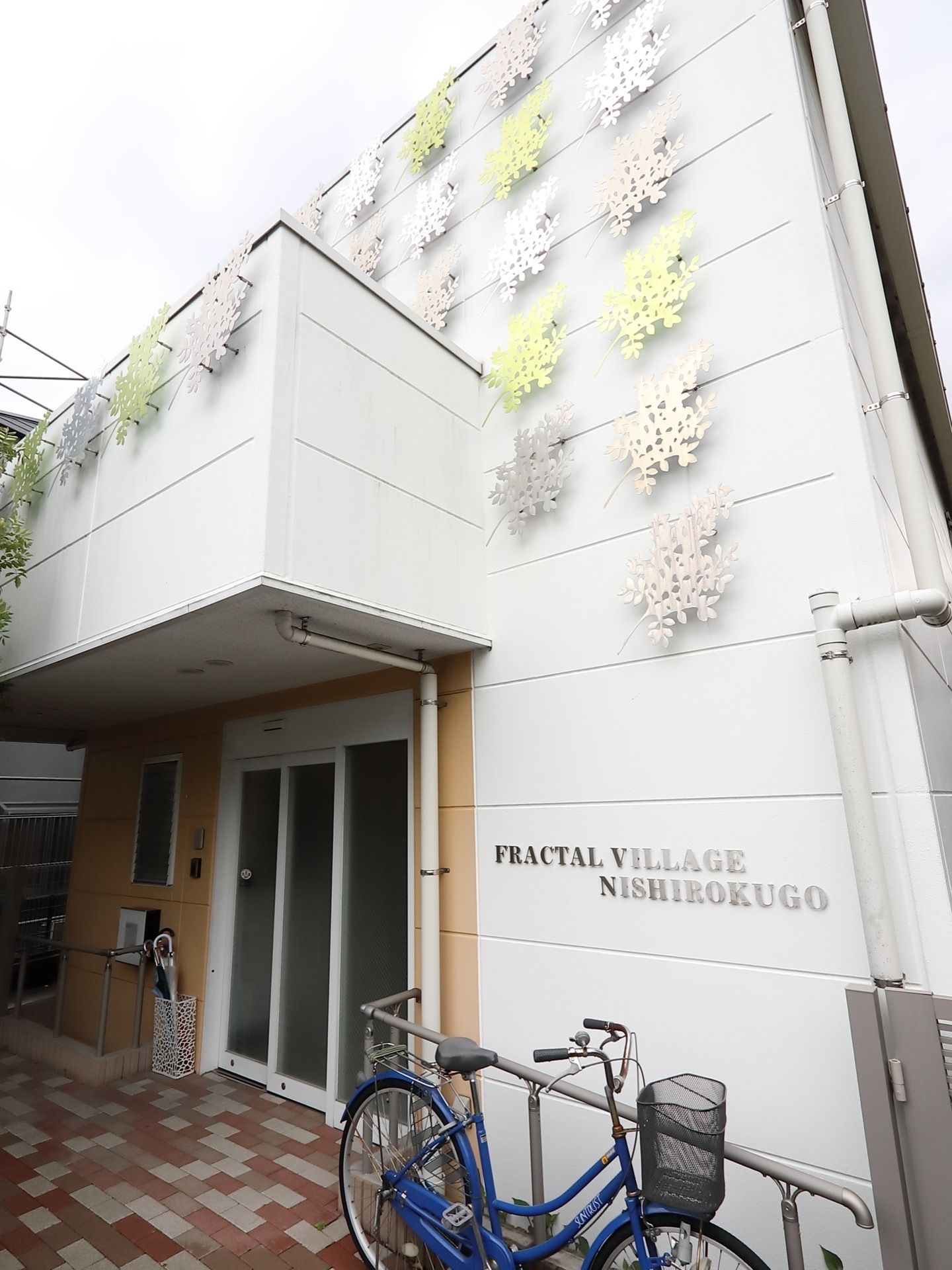 エントランスには、大きなひさしが設置されている。自動ドアが玄関扉として採用されており、手すりが両サイドの外壁に沿って取りつけられている。