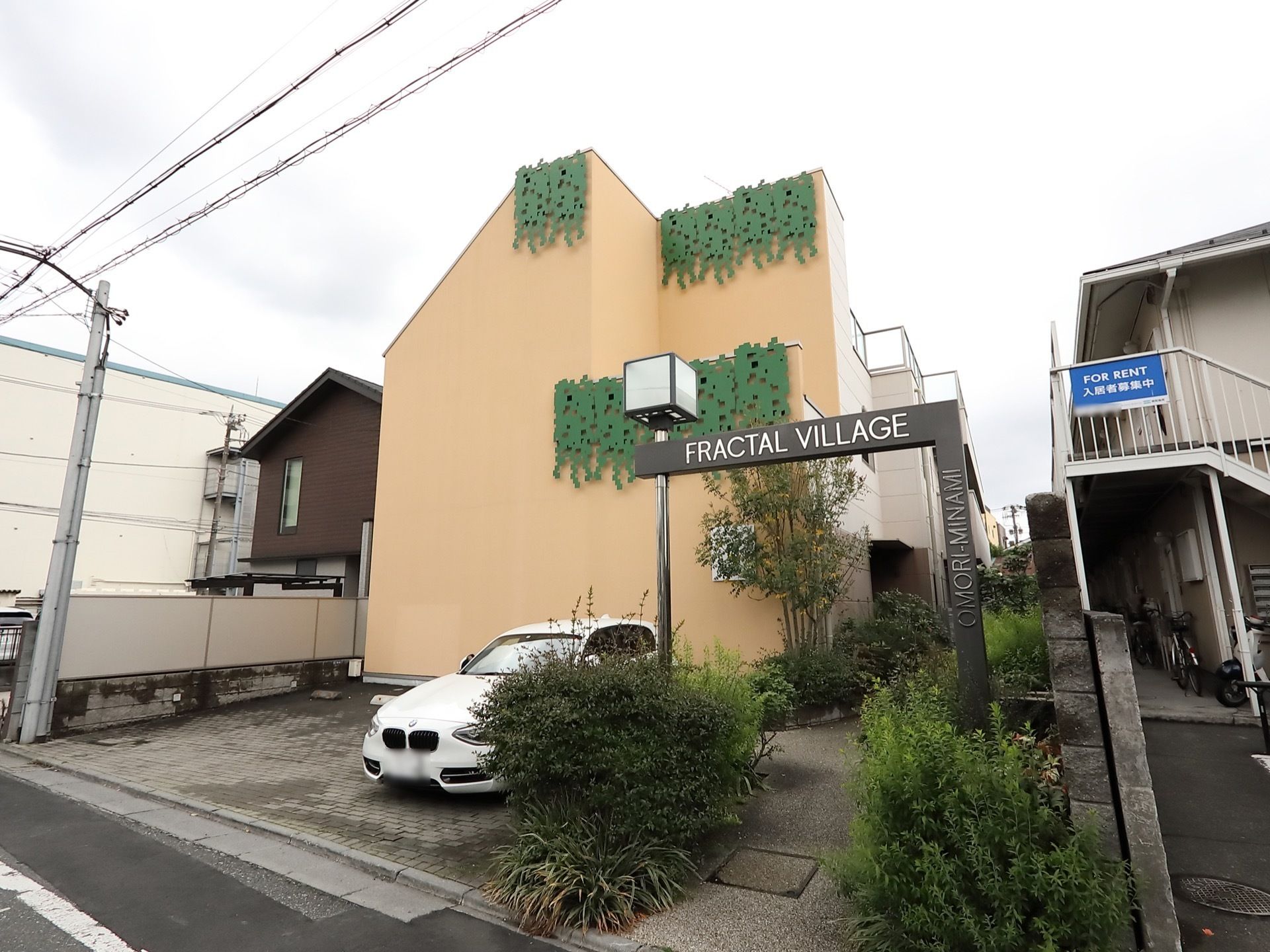 道路に面した場所に立地する、２階建ての施設である。駐車場が完備されている。緑が随所に設けられている。