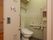共用トイレのドアには、大きな手書きの赤文字でトイレを示す貼り紙がしてある。個室内には便器と手洗い場がある。