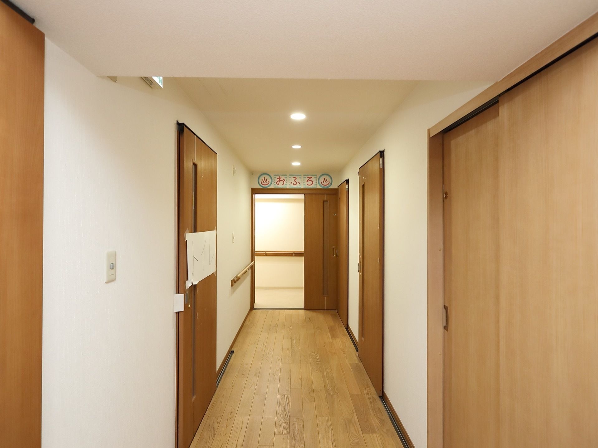 通路の床や扉などの建具は、ナチュラル系の色の木材が使われている。浴室の入り口の案内は手作りで、あたたかみがある。