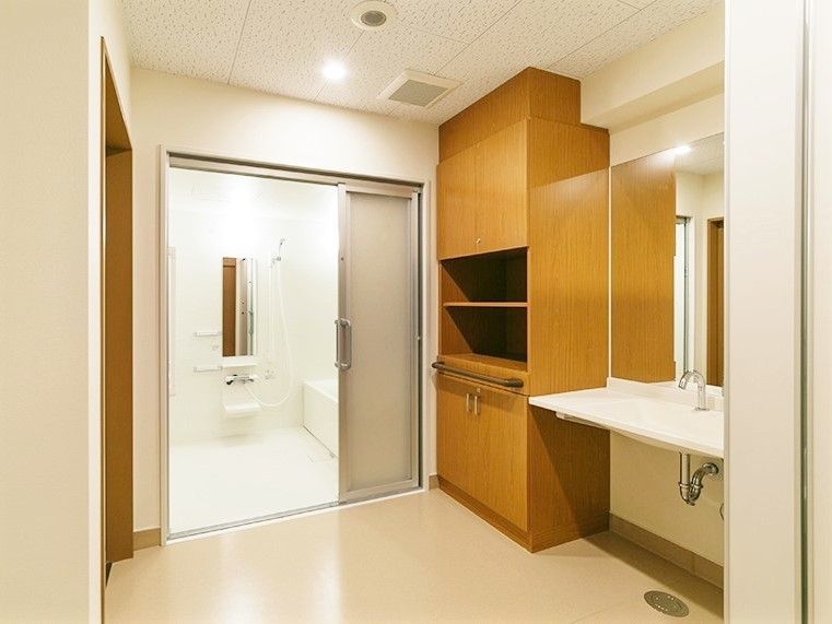 カンタンな収納と洗面台がついた施設内の浴室入り口。水回り設備の写真