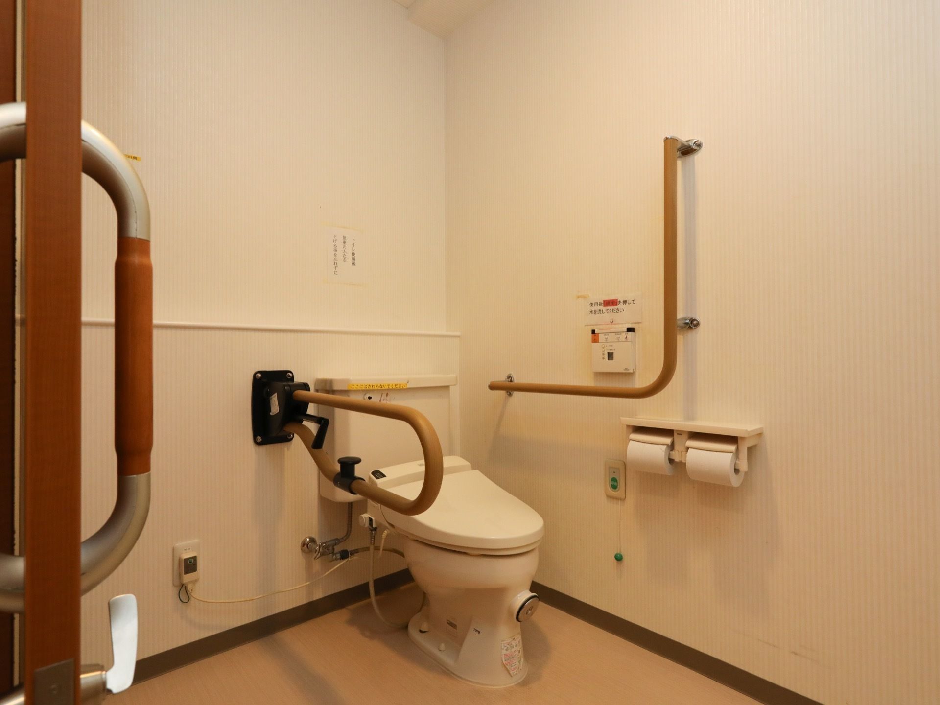 淡い色調で統一され、清潔に保たれたトイレである。便座の両側に手すりが設置され、ナースコールが取りつけられている。