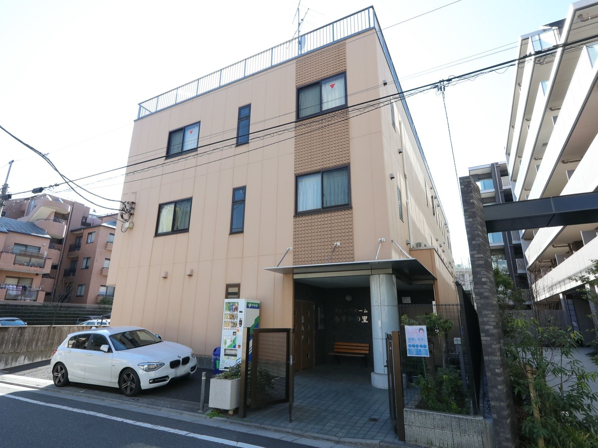 住宅街の中に佇むベージュの建物である。周囲に高層の建物はなく、隣接するマンションとも距離が取られ、圧迫感のない場所に建っている。