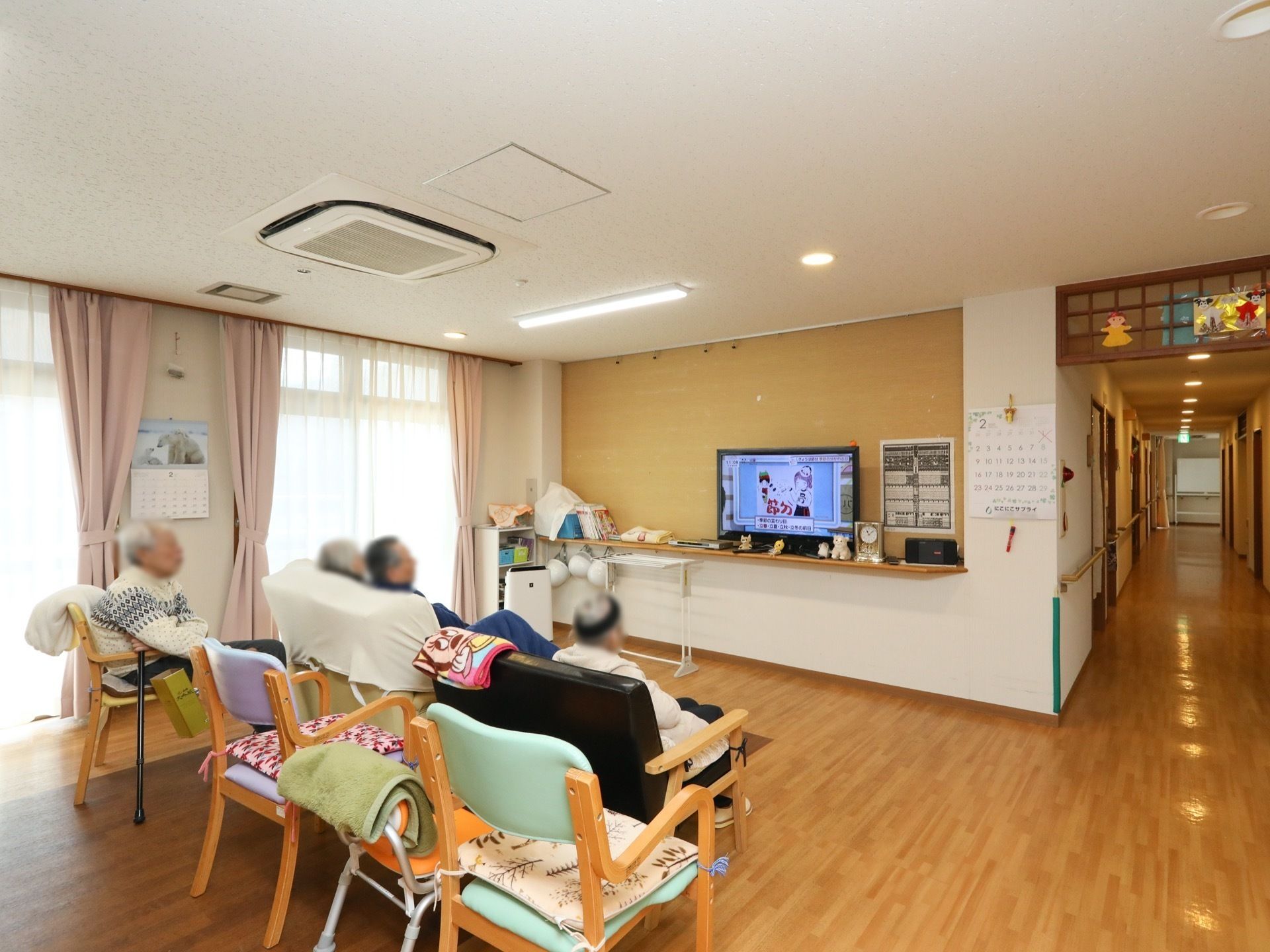 大きな窓の傍にテレビとベンチが並べられた共有スペース