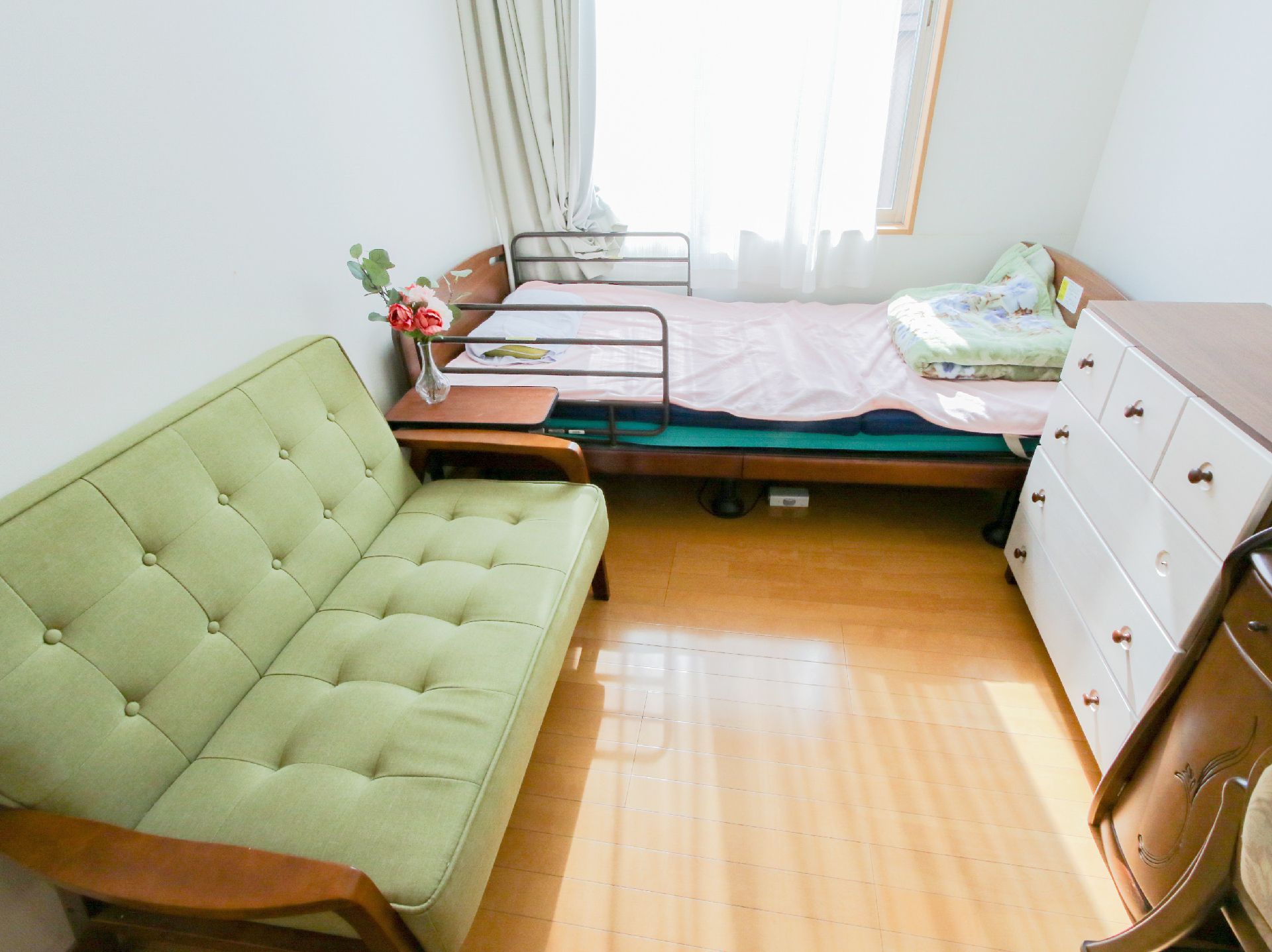 緑のソファーとベッドが置かれた白い壁の部屋
