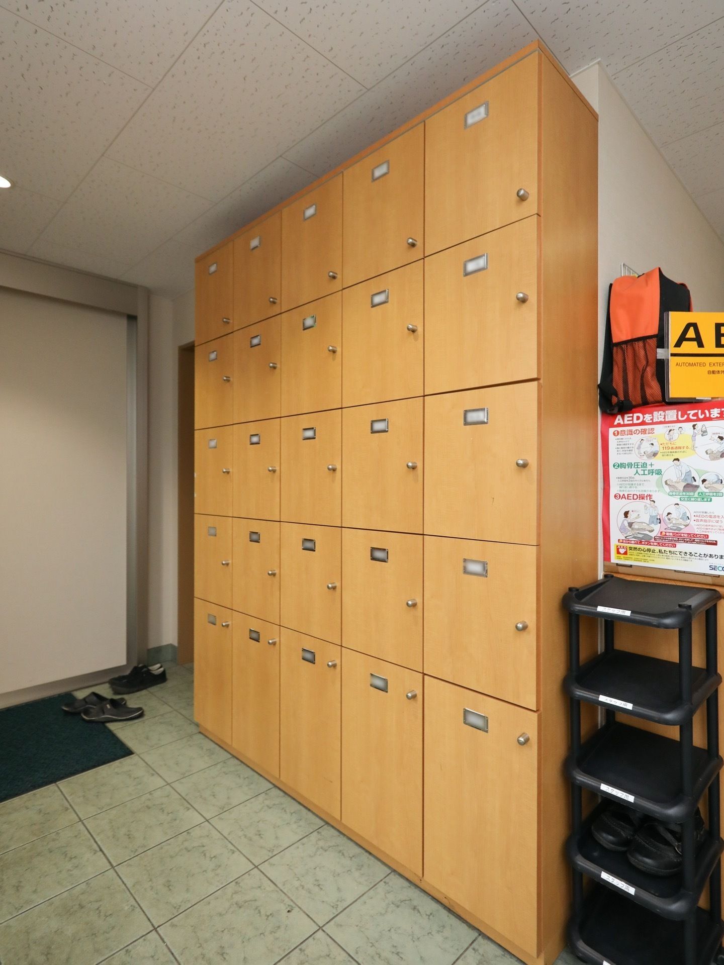 縦、横に５区画で天井の高さある靴箱である。それぞれに扉が付いている。横には黒いスリッパ入れが置かれている。