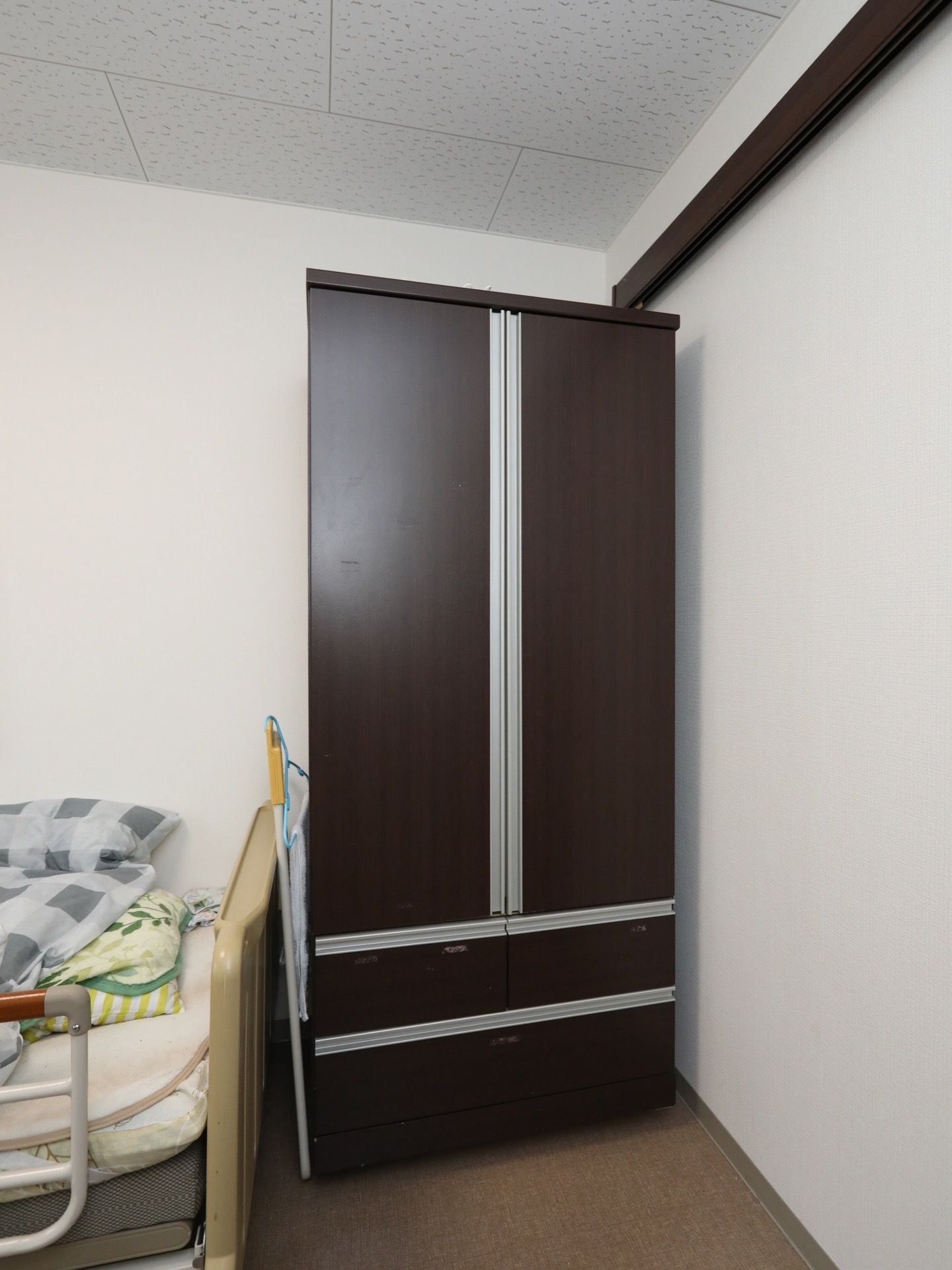 居室に設置された収納タンスである。下の方が２段の引き出しで、上部は観音開きの扉が付いたロッカーとなっている。