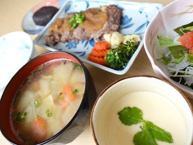 肉料理をメインとした食事。茶わん蒸しやサラダ、みそ汁や白いご飯もある。