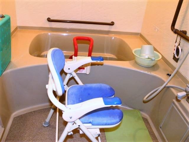 一人用の浴槽が設置された浴室。シャワーや洗面器、シャワーチェアもあり、手すりが壁についている。