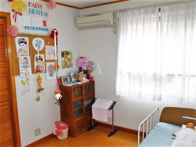 エアコンやベッド、収納家具が付いた居室にはカラフルな塗り絵や花が飾られている。