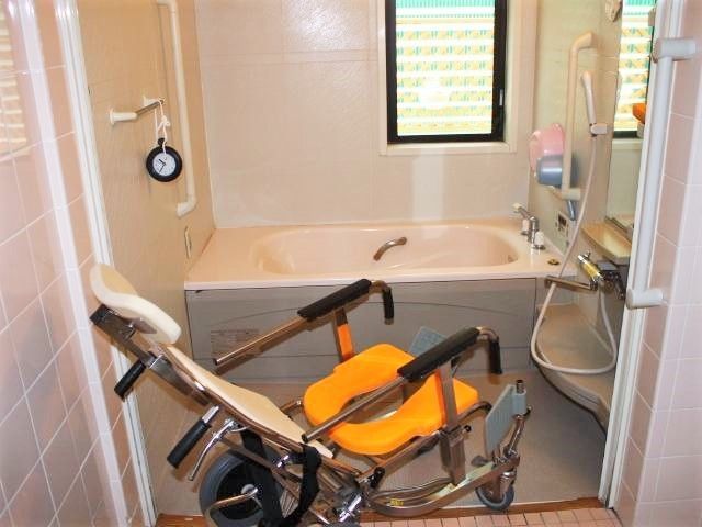 一人用の浴槽が設置された浴室。シャワーや浴室用車いすもあり、手すりが壁についている。