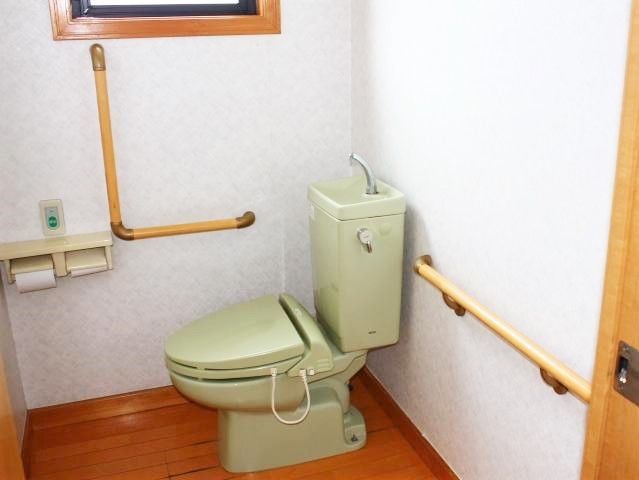 鶯色のトイレが設置され、手すりや呼び出しボタンも付いた広いスペース。