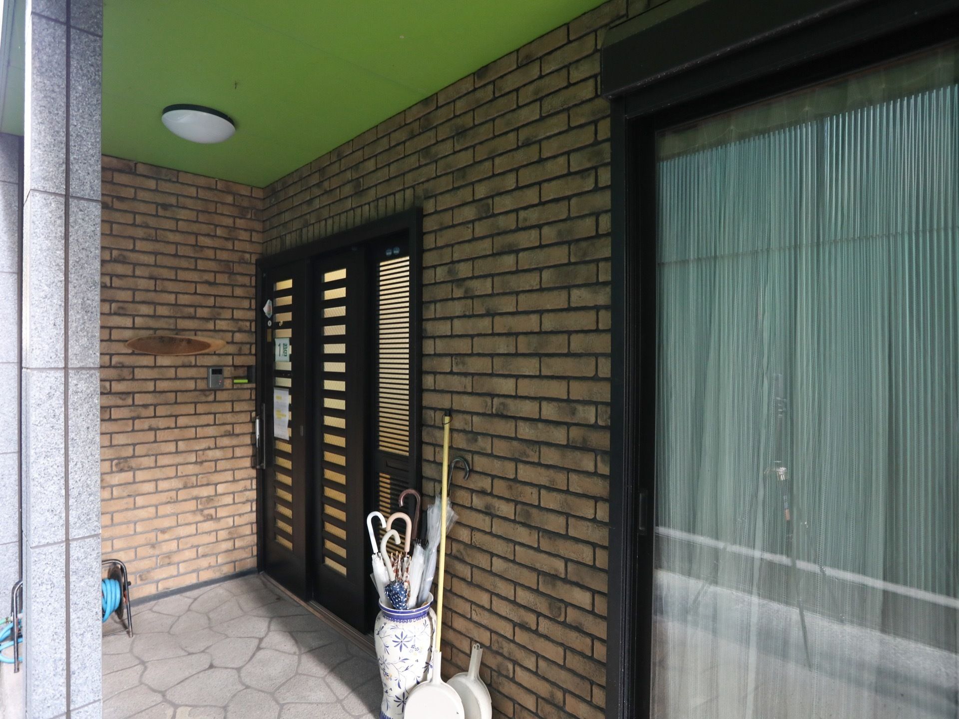 エントランスの天井は緑色でライトが設置されている。黒いドアの周囲はレンガ調となっており、ドアはスライド式である。
